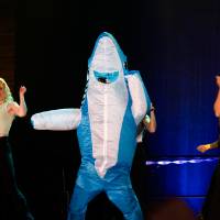 A student in a shark costume on stage.